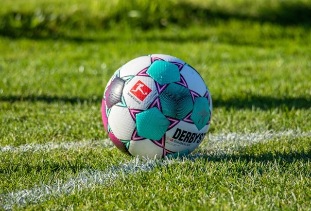 A Derbystar Bundesliga match ball sitting on the turf of a football pitch.
